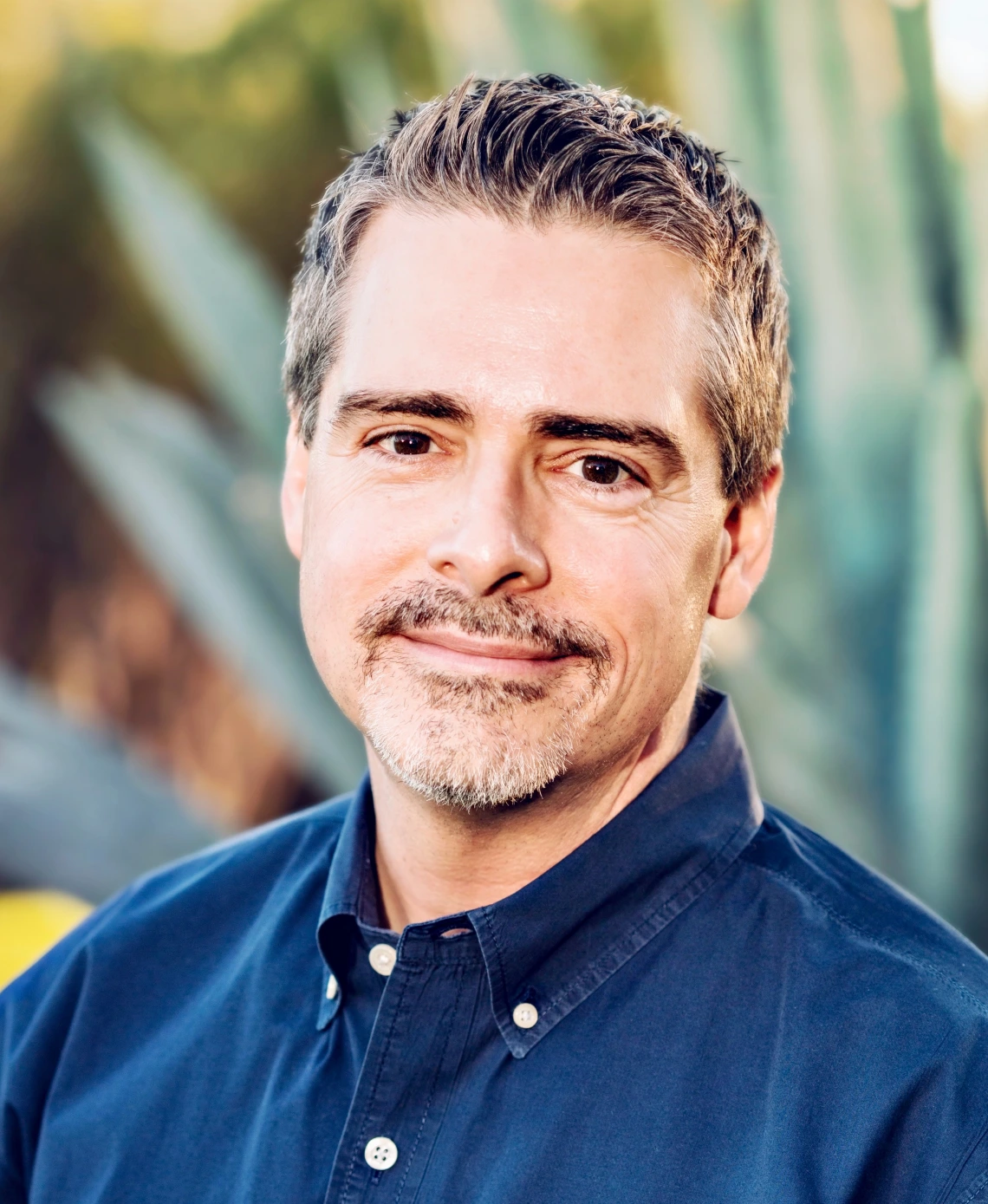 Professional Photo of Dr. Kory Floyd wearing a blue collared shirt against a background of an agave plant